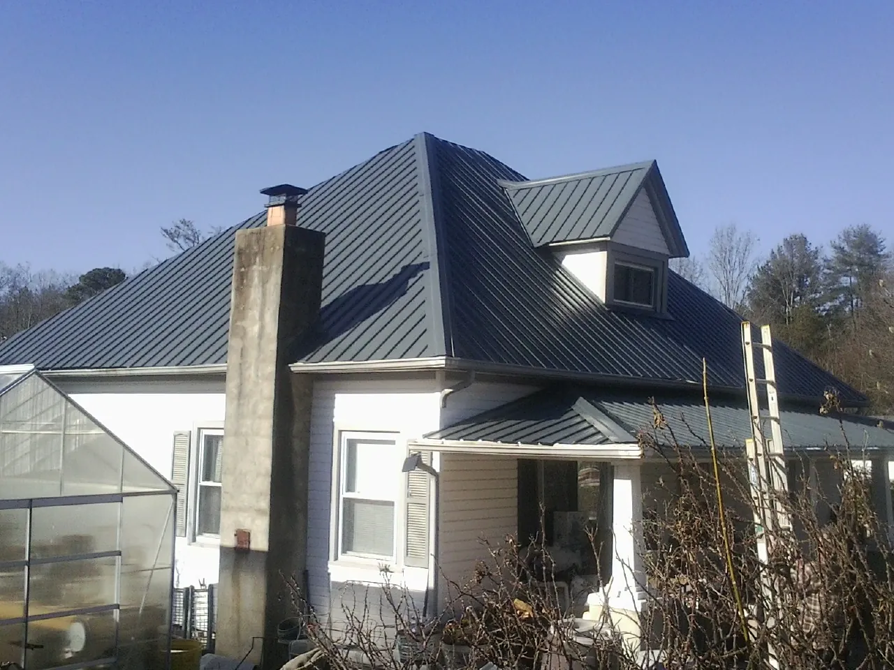 Dark blue standing seam metal roof on a white farmhouse with dormer — Slate & Tile Roof Repair by Roofing Brothers in Traphill