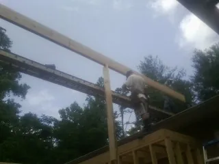 Carpenter setting a ridge beam over a new addition frame — Ice Dam Removal by Roofing Brothers in Traphill