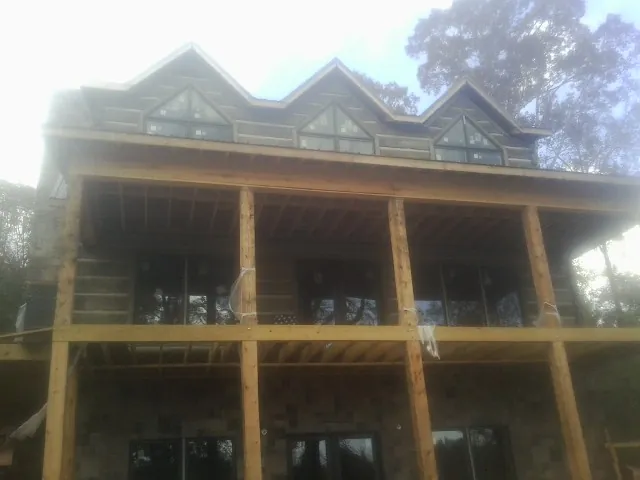 Dormers and porch framing on a large log home under construction — Roof Coating work by our crew in Traphill