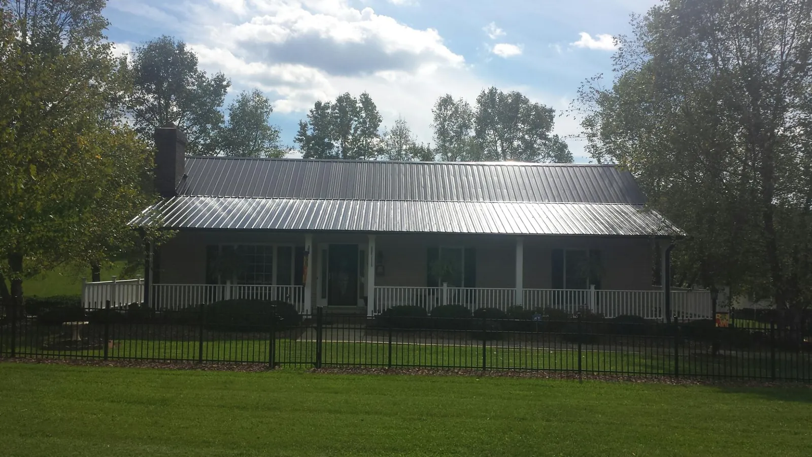 Gray metal roof on a brick ranch with a full width front porch — Gutter Guard Installation work by our crew in Traphill